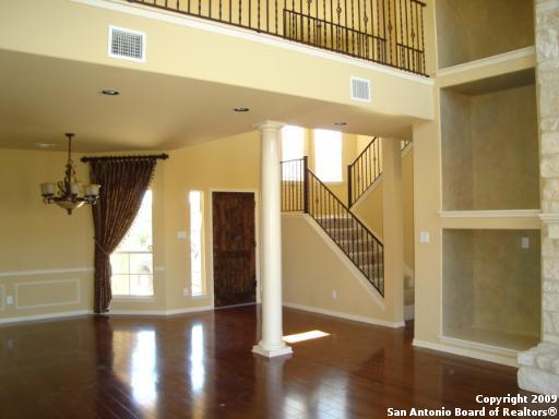 entryway with decorative columns, a high ceiling, visible vents, and wood finished floors