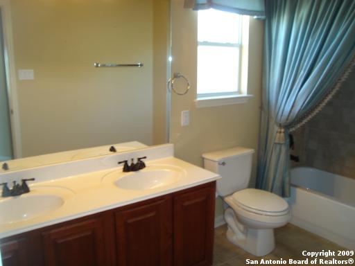 bathroom with double vanity, toilet, shower / bath combo with shower curtain, and a sink