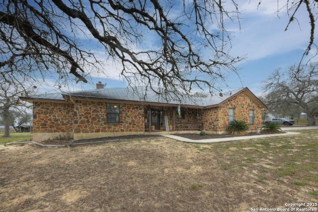 view of front of property featuring a front yard, stone siding, and a chimney