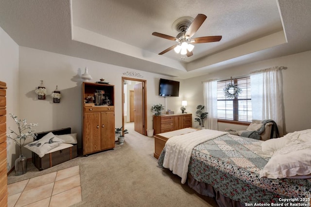 bedroom with light colored carpet, a textured ceiling, a raised ceiling, and a ceiling fan