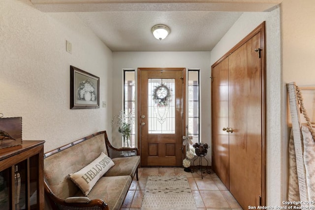 entrance foyer featuring light tile patterned floors, a textured ceiling, and a textured wall