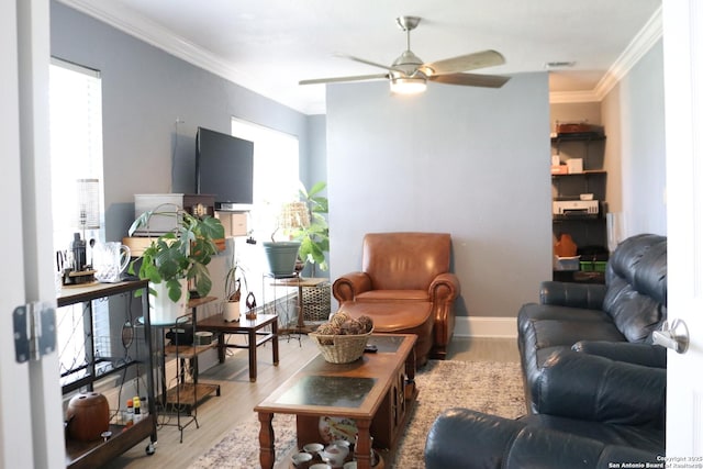 living area with baseboards, a ceiling fan, light wood-style flooring, and crown molding