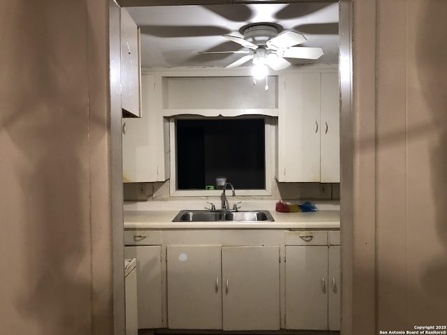 kitchen with ceiling fan, light countertops, white cabinetry, and a sink