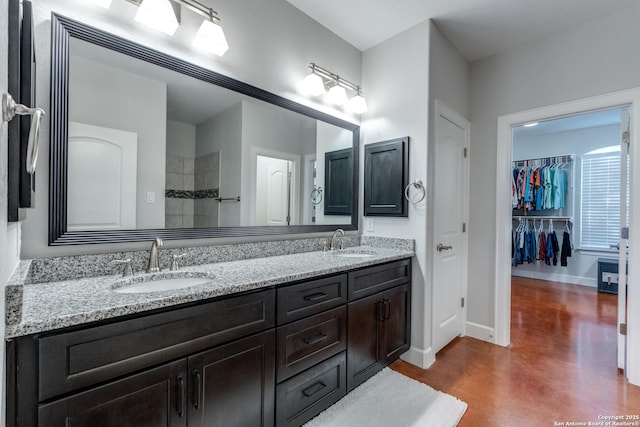 bathroom with finished concrete floors, double vanity, baseboards, and a sink