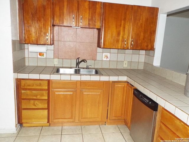 kitchen featuring brown cabinetry, light tile patterned flooring, a sink, stainless steel dishwasher, and backsplash