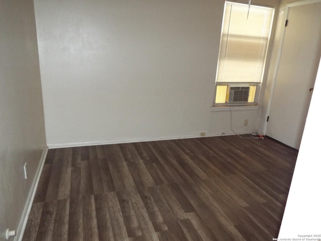 unfurnished room featuring cooling unit, baseboards, and wood finished floors