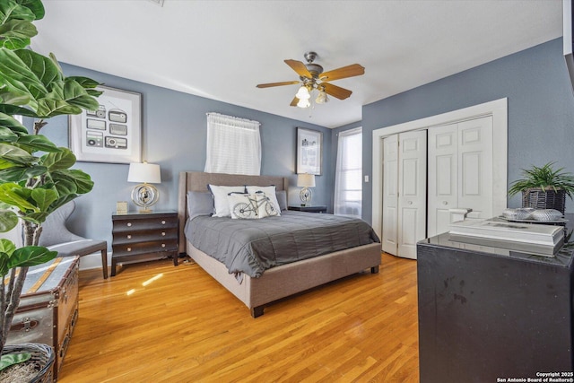 bedroom with a closet, baseboards, a ceiling fan, and light wood finished floors