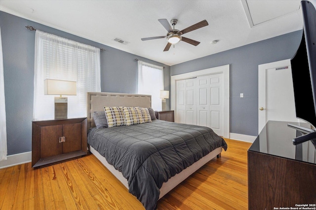 bedroom featuring a ceiling fan, baseboards, visible vents, light wood-style flooring, and a closet