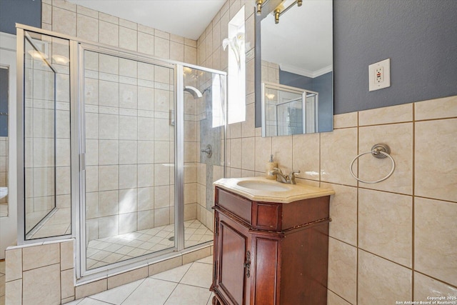 full bathroom featuring a stall shower, tile walls, crown molding, tile patterned flooring, and vanity