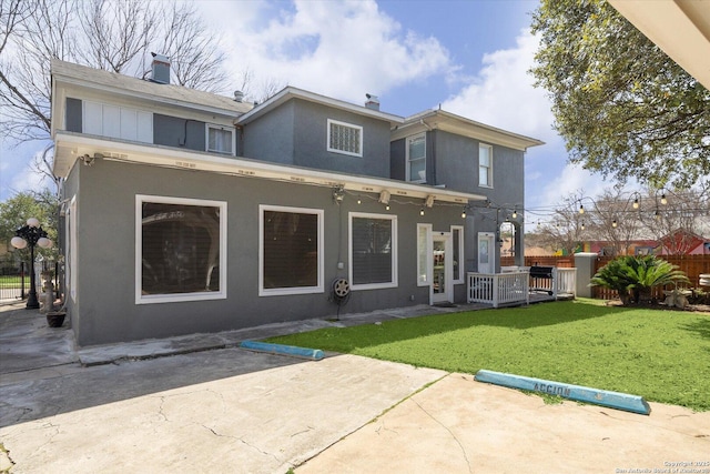 rear view of house with a yard, a patio, fence, and stucco siding