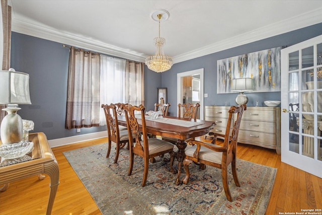 dining space featuring baseboards, an inviting chandelier, wood finished floors, and crown molding