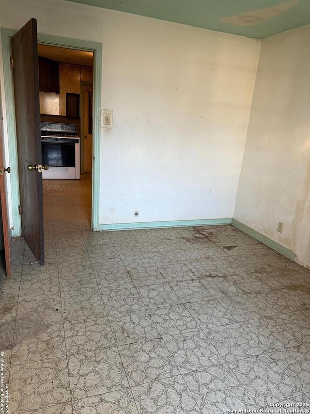 spare room featuring light floors and baseboards