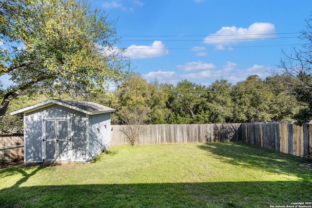 view of yard with an outdoor structure, a fenced backyard, and a shed