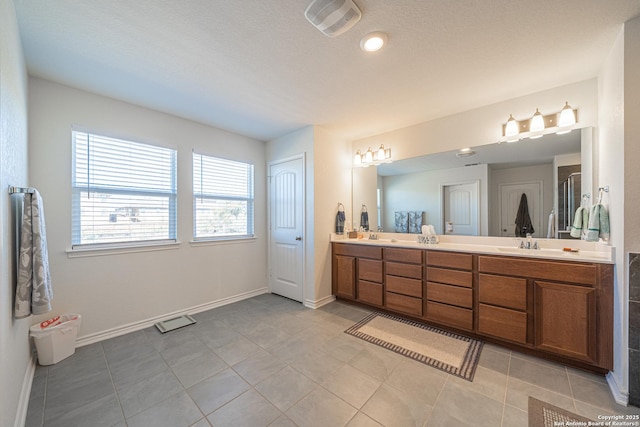 bathroom with visible vents, a stall shower, a sink, double vanity, and baseboards