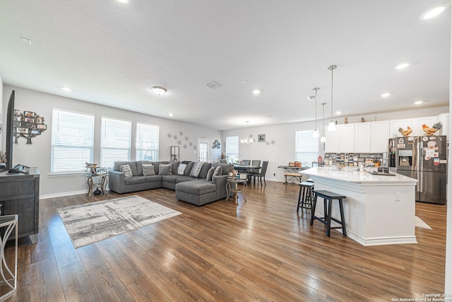 living room with visible vents, recessed lighting, baseboards, and wood-type flooring