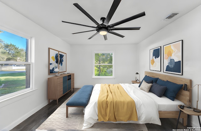 bedroom with ceiling fan, dark wood-style floors, visible vents, and baseboards