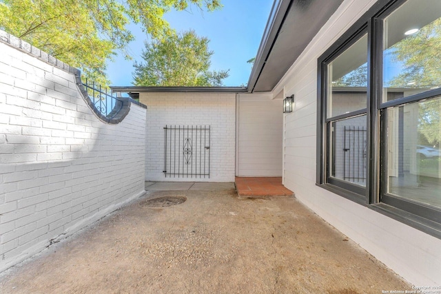 doorway to property featuring a patio and brick siding