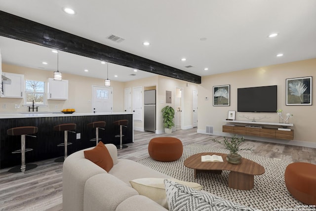 living area featuring light wood finished floors, visible vents, baseboards, beam ceiling, and recessed lighting