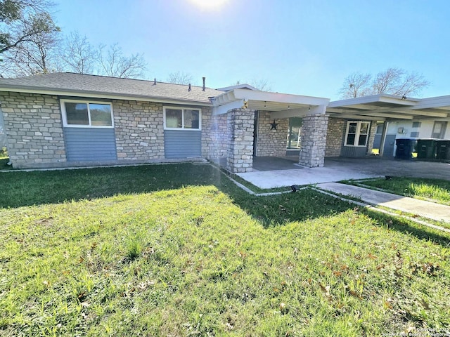 rear view of property with stone siding, a lawn, and a patio