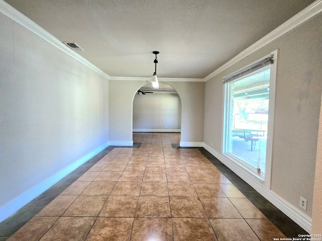 unfurnished dining area featuring baseboards, visible vents, arched walkways, ornamental molding, and tile patterned flooring