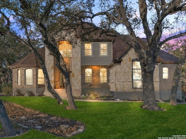 view of front facade with stone siding and a lawn