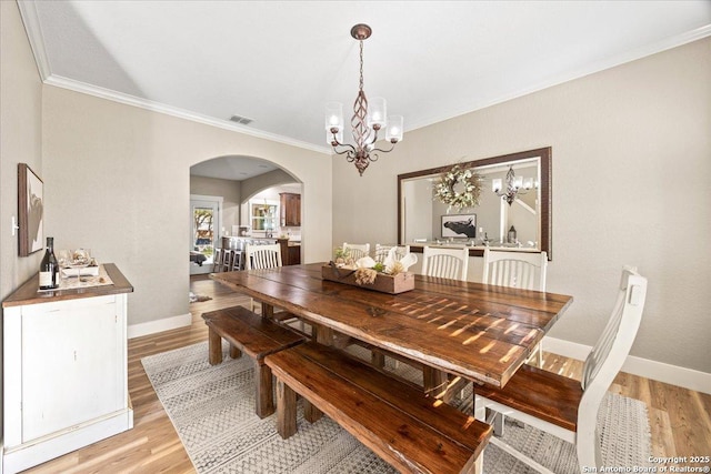 dining space featuring arched walkways, visible vents, baseboards, and light wood-style floors