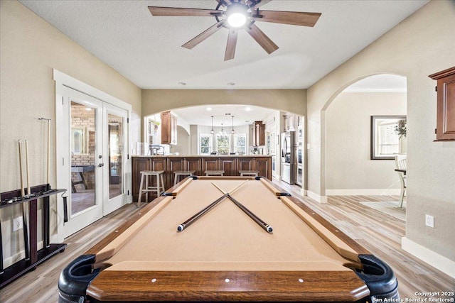 recreation room featuring baseboards, light wood-style flooring, arched walkways, pool table, and french doors