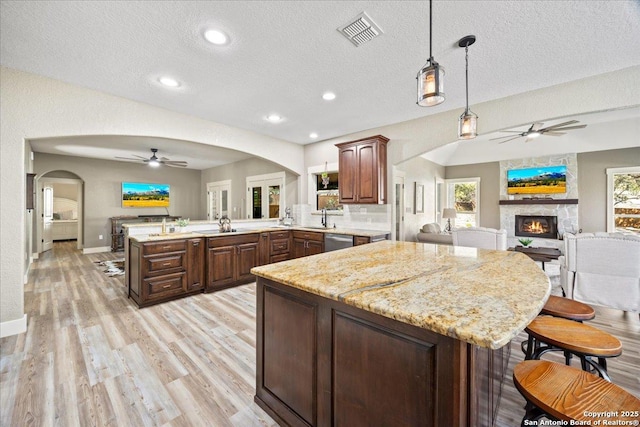 kitchen with visible vents, a peninsula, arched walkways, dishwasher, and open floor plan