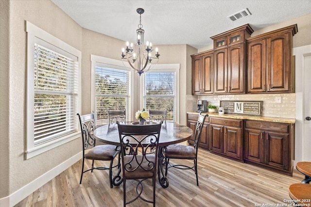 dining area featuring baseboards, visible vents, a chandelier, and light wood-type flooring