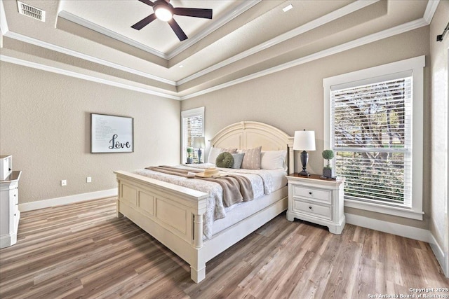 bedroom featuring visible vents, multiple windows, and a raised ceiling