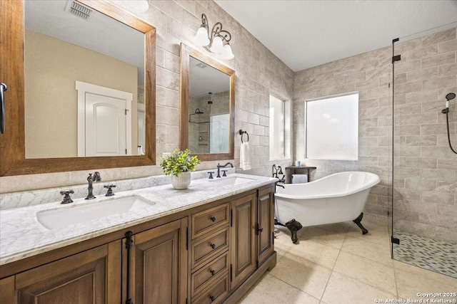 bathroom with a tile shower, visible vents, tile walls, and a sink