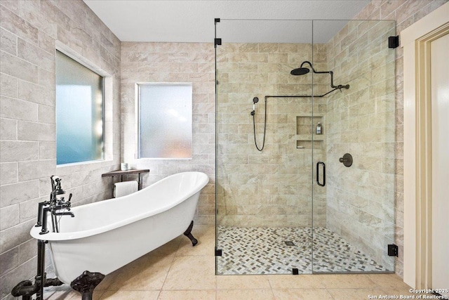 full bath featuring tile patterned floors, a stall shower, a freestanding bath, and tile walls