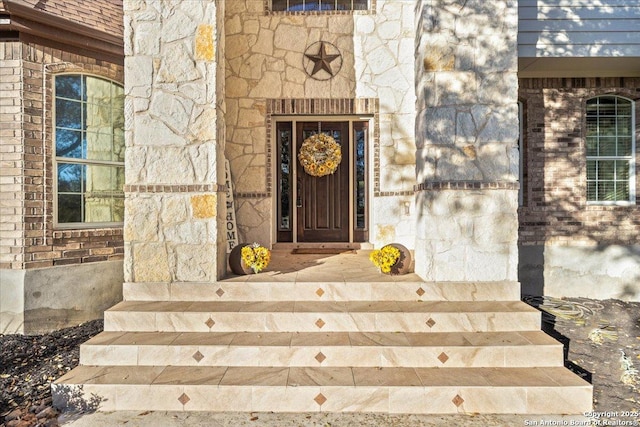 view of exterior entry featuring stone siding, brick siding, and roof with shingles