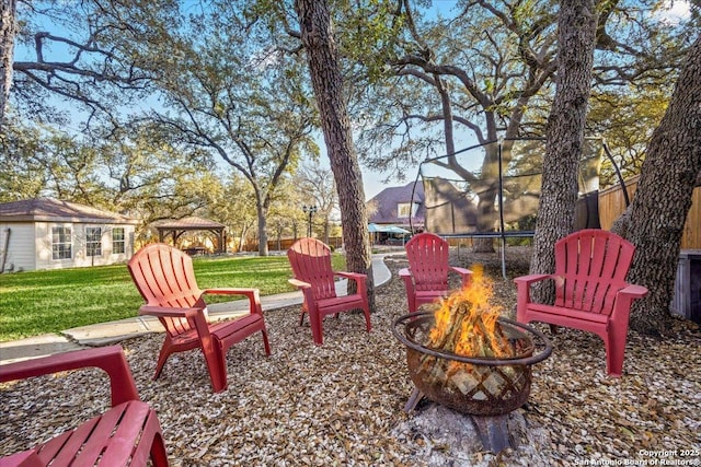 view of yard featuring a trampoline and an outdoor fire pit