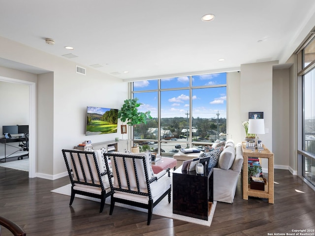 living room with visible vents, floor to ceiling windows, baseboards, and wood finished floors