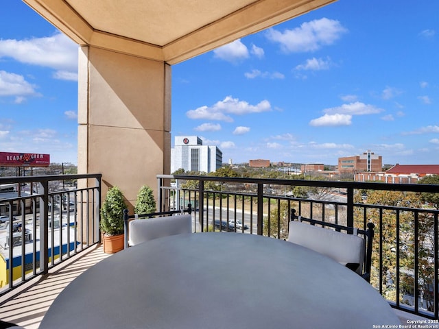 balcony with outdoor dining space and a city view