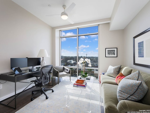 office area with a ceiling fan, a wall of windows, and wood finished floors