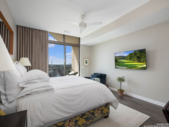 bedroom featuring a wall of windows, a ceiling fan, wood finished floors, baseboards, and visible vents