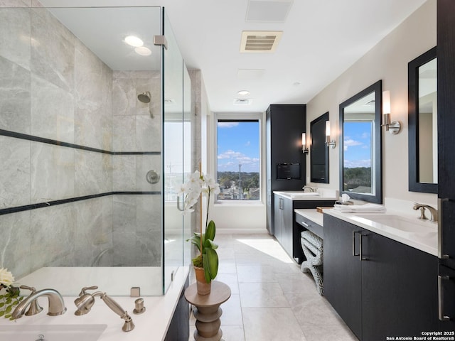 full bath featuring visible vents, a shower stall, two vanities, and a sink