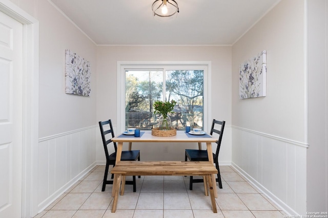 dining room with light tile patterned floors, wainscoting, and crown molding