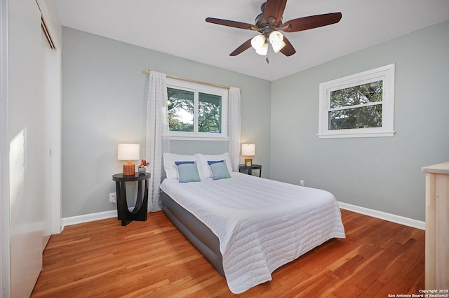 bedroom with a ceiling fan, baseboards, and light wood-type flooring