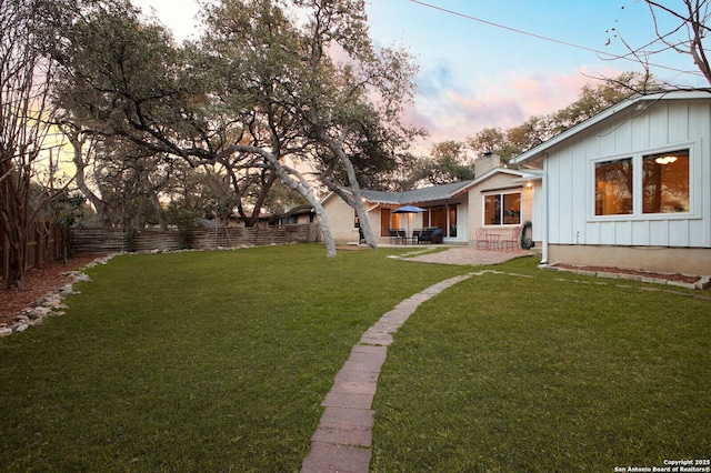 yard at dusk with a patio area and fence