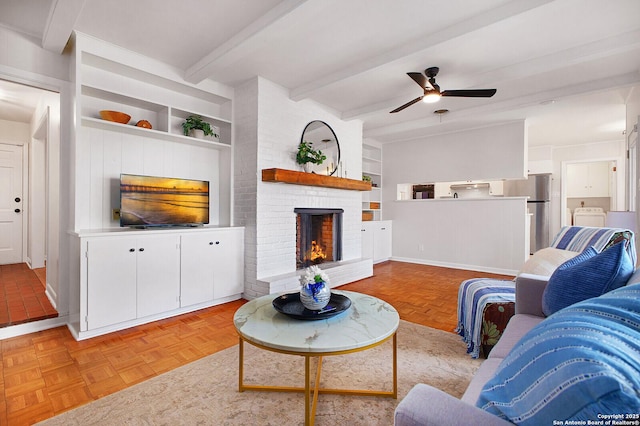 living room with a brick fireplace, baseboards, ceiling fan, built in features, and beamed ceiling