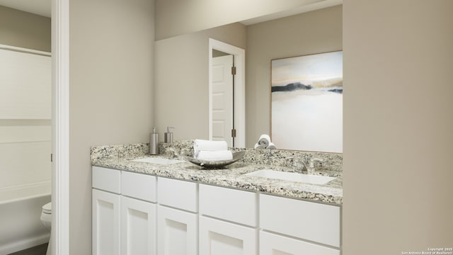 bathroom with double vanity, toilet, and a sink