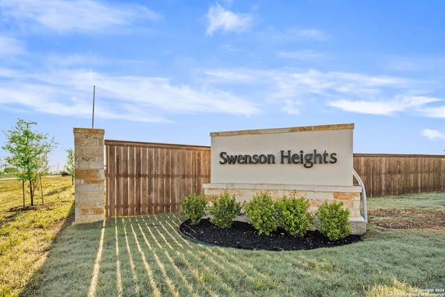 community / neighborhood sign featuring a yard and fence