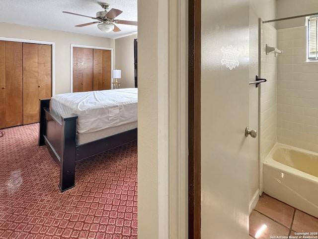 bedroom featuring ceiling fan, a textured ceiling, and multiple closets