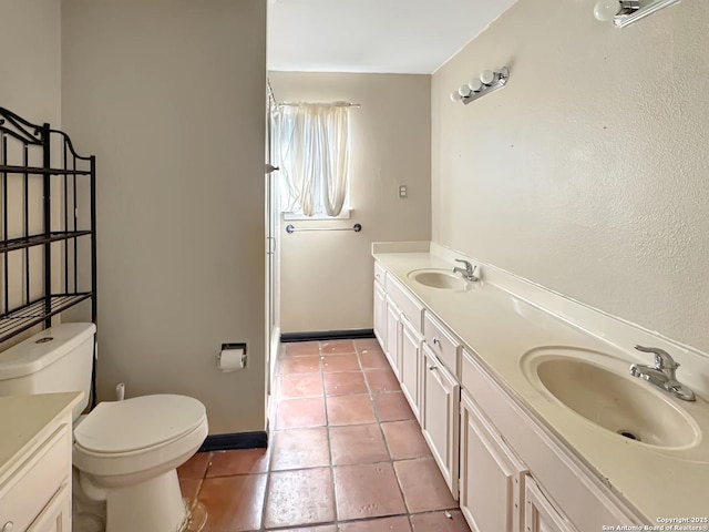 bathroom featuring tile patterned floors, toilet, double vanity, and a sink