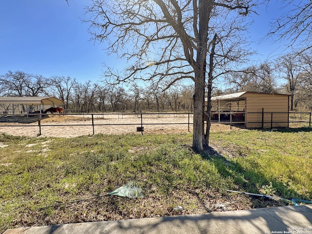 view of yard with a detached carport, an outdoor structure, and fence