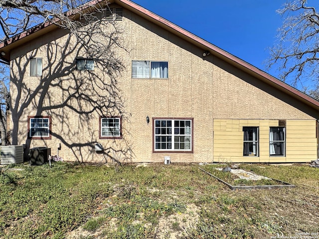 view of side of property featuring a yard, central AC unit, and stucco siding