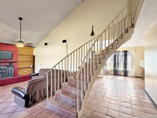 staircase with high vaulted ceiling, a ceiling fan, and tile patterned flooring